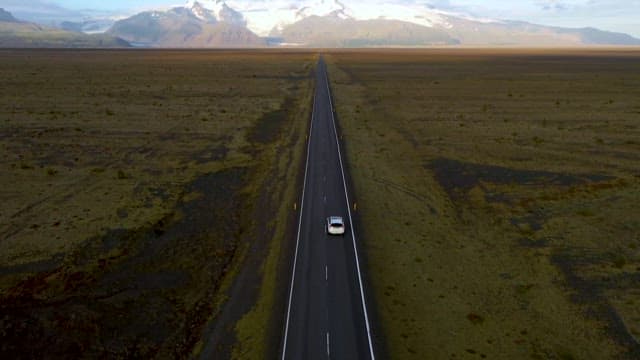 Car Driving Throgh Straight Road Spread Out Across a Vast Plain