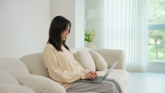 Woman using a laptop on a sofa in the living room