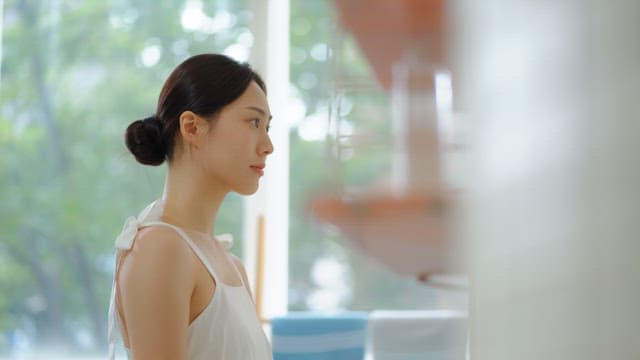 Woman tidying up her face with an eyebrow razor in a bright room