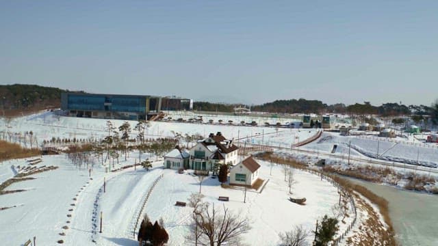 Snow-covered landscape with buildings and trees on a clear day