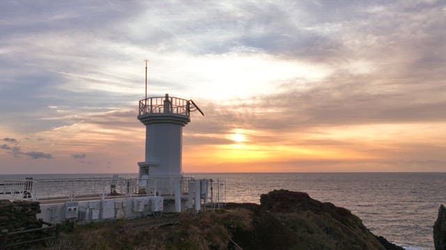 Lighthouse on a coastal cliff at sunset