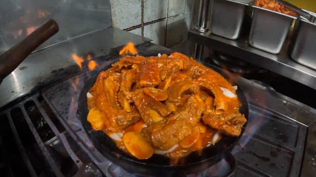Spicy pork ribs cooked on a stovetop in a restaurant kitchen