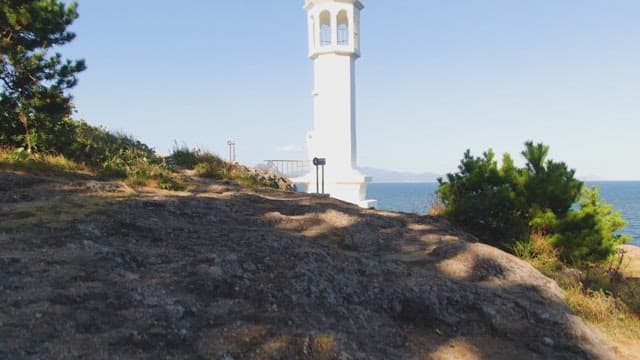 Lighthouse by the sea with distant mountains