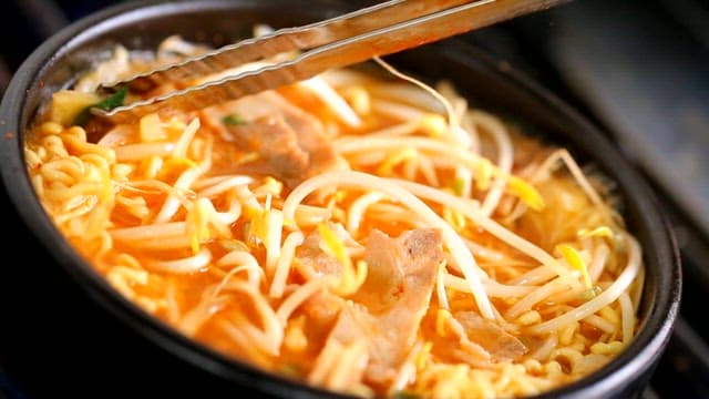 Ramyeon boiling with bean sprouts and pork belly