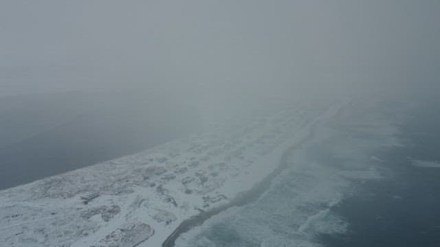 Winter coastline with icy waters and snowy settlement