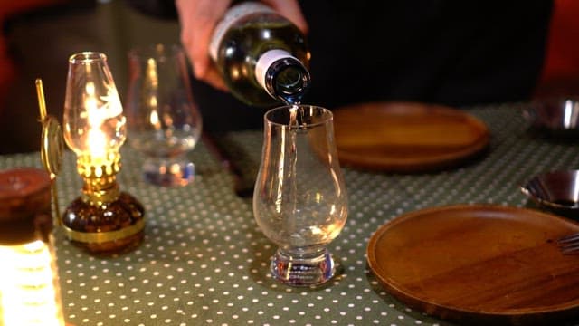 Pouring white wine into a glass on a cozy dinner table with lanterns
