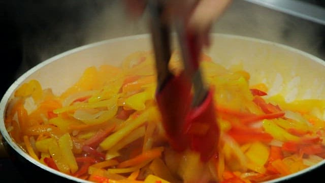 Frying yellow and red bell peppers in a frying pan