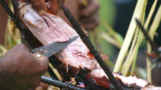 Grilled whole pig barbecue being sliced outdoors