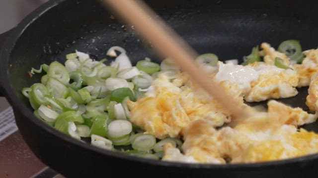 Cooking Scrambled Eggs and Green Onions in a Frying Pan