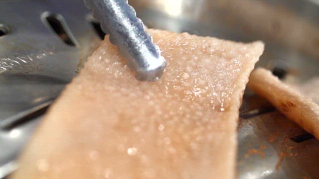 Grilling pork rinds on a metal grill