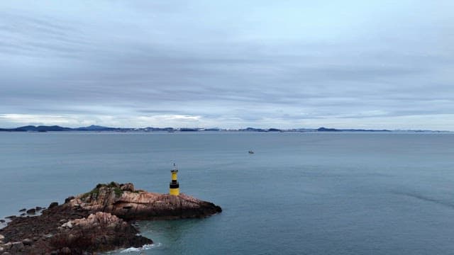 Yellow lighthouse on a rocky island in the sea