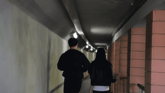Two people jogging in a dimly lit tunnel