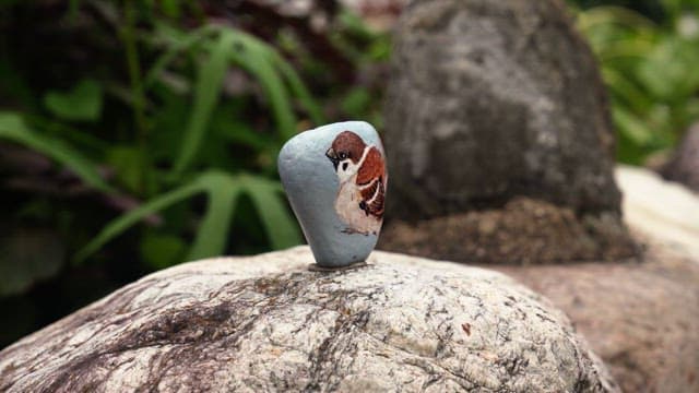 Stone depicting a sparrow erected on a rock outdoors