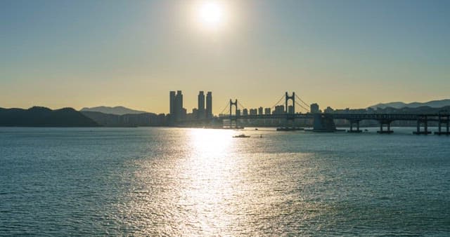 Evening to night view of the sea with city and bridge visible
