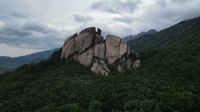 Rock amidst the lush Geumgangsan Mountains under a cloudy sky