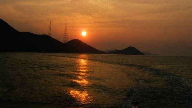Mountain Silhouette at Dusk with the Red Sky and Sea