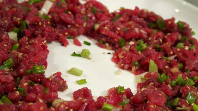 Sliced octopus on top of the delicious beef tartare on a plate