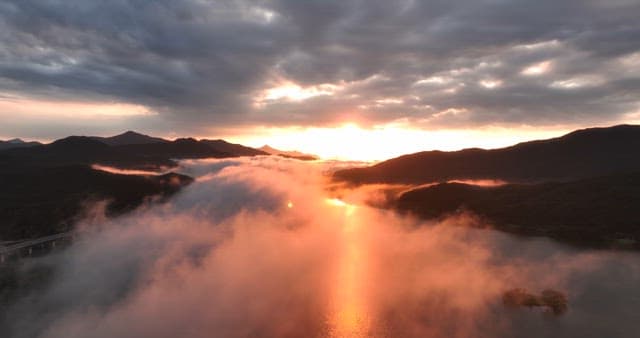Sunset over mountains with misty clouds