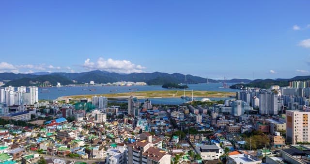 Cityscape with buildings, mountains and sea under the sky from day to night