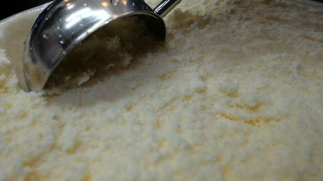 Scooping vanilla ice cream from a tub