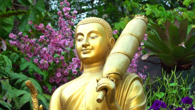 Golden Buddha statue amidst colorful flowers