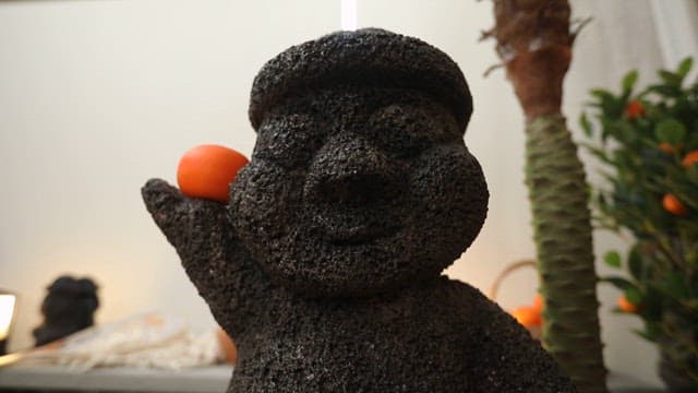 Radish and conch displayed on a table with a Dolhareubang statue