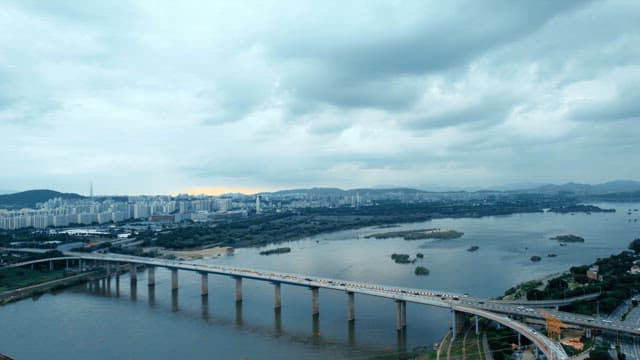 Bridge with cars passing over a river with apartments