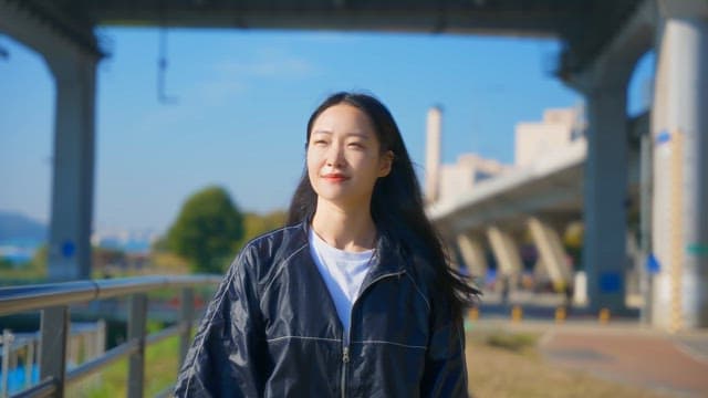 Woman walking under a bridge on a sunny day