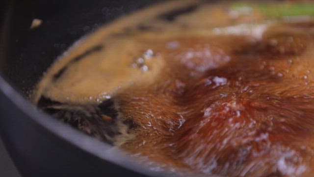 Simmering broth with soy sauce in a pot