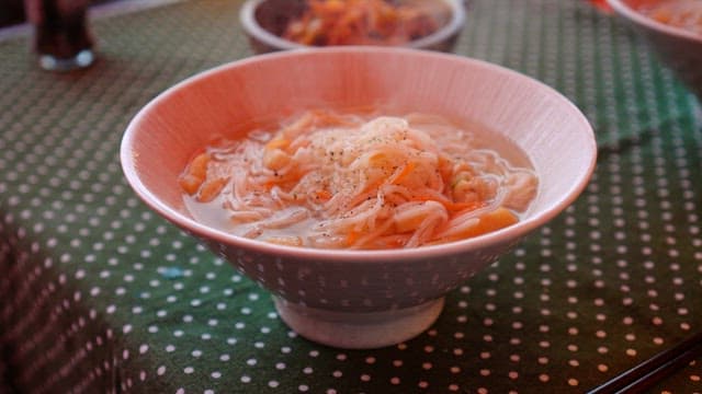 Close-up of noodles being prepared in a bowl.