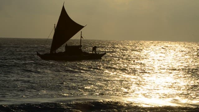 Small sailboat on the sea at sunset