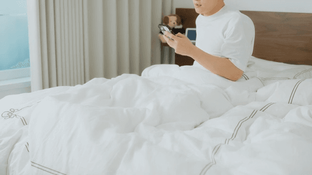 Man waking up and checking phone in bed
