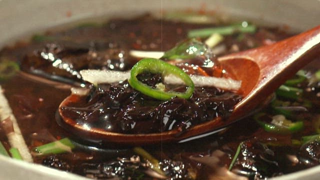 Refreshing chilled seaweed soup in a bowl with a wooden spoon