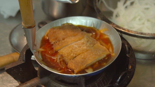 Making katsudon with pork cutlet and egg on the stove