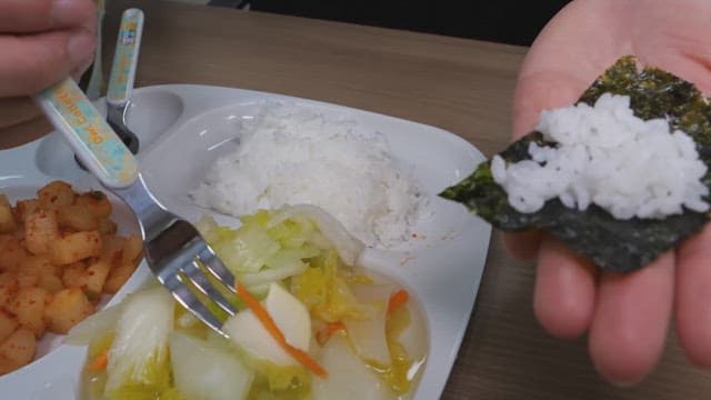 Eating rice and white kimchi on top of seaweed