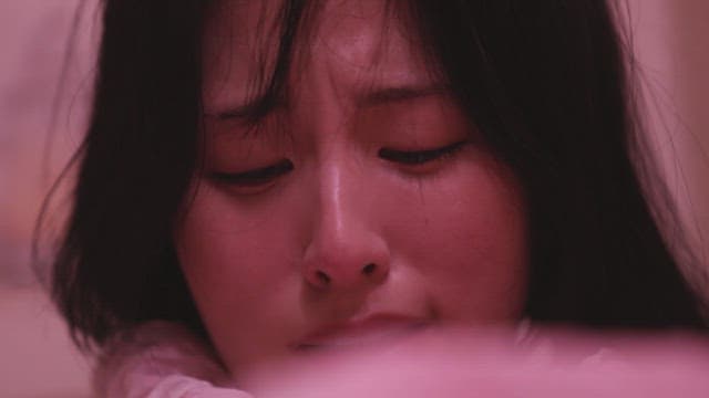 Woman sobbing under a pink light