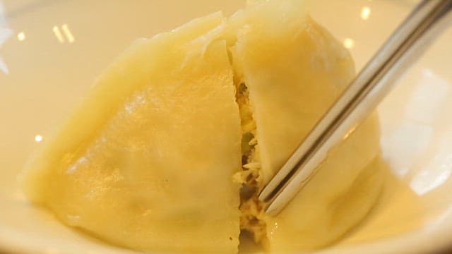 Pyeongyang dumpling being cut open with chopsticks