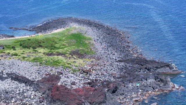 Scenic coastal view of rocky cape and boat passing nearby at sea