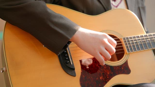Student playing an acoustic guitar