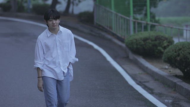 Man walking down the street and stopping in front of a garbage dump.