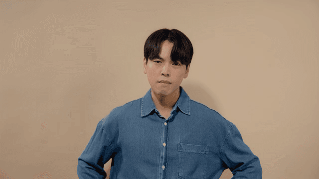 Man in a denim shirt looking straight ahead with a serious expression