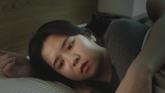 Woman lying in bed with worried expression