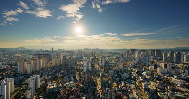 Busy traffic and sky in downtown Daegu with densely packed buildings from evening to night