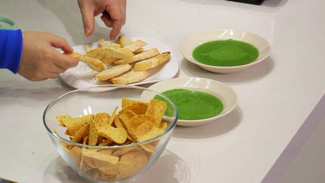 Bread being dipped into green spinach dip