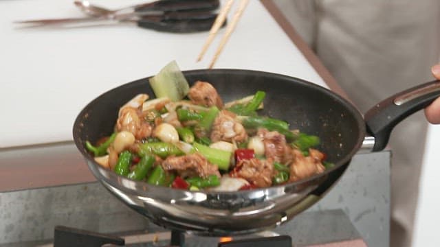 Stir-frying  chicken with green onion on a stove