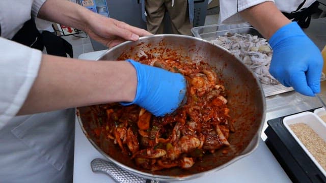 Mixing spicy seasoning and webfoot octopus in a large bowl