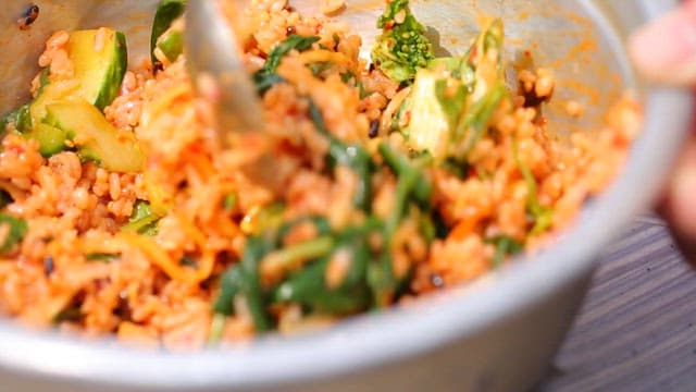 Spoonful of delicious bibimbap is mixed in a brass bowl
