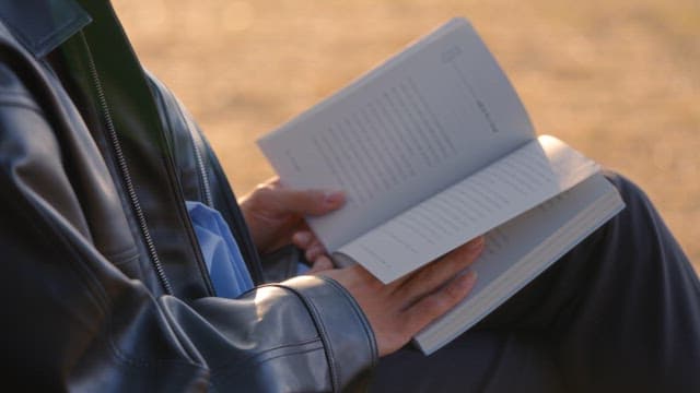 Person reading a book outdoors