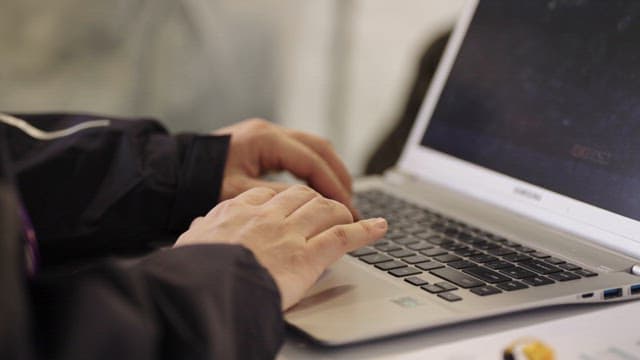 Person Working on Laptop in Long-Sleeved Clothes