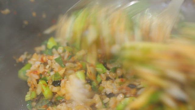 Stirring vegetables and rice in a hot wok